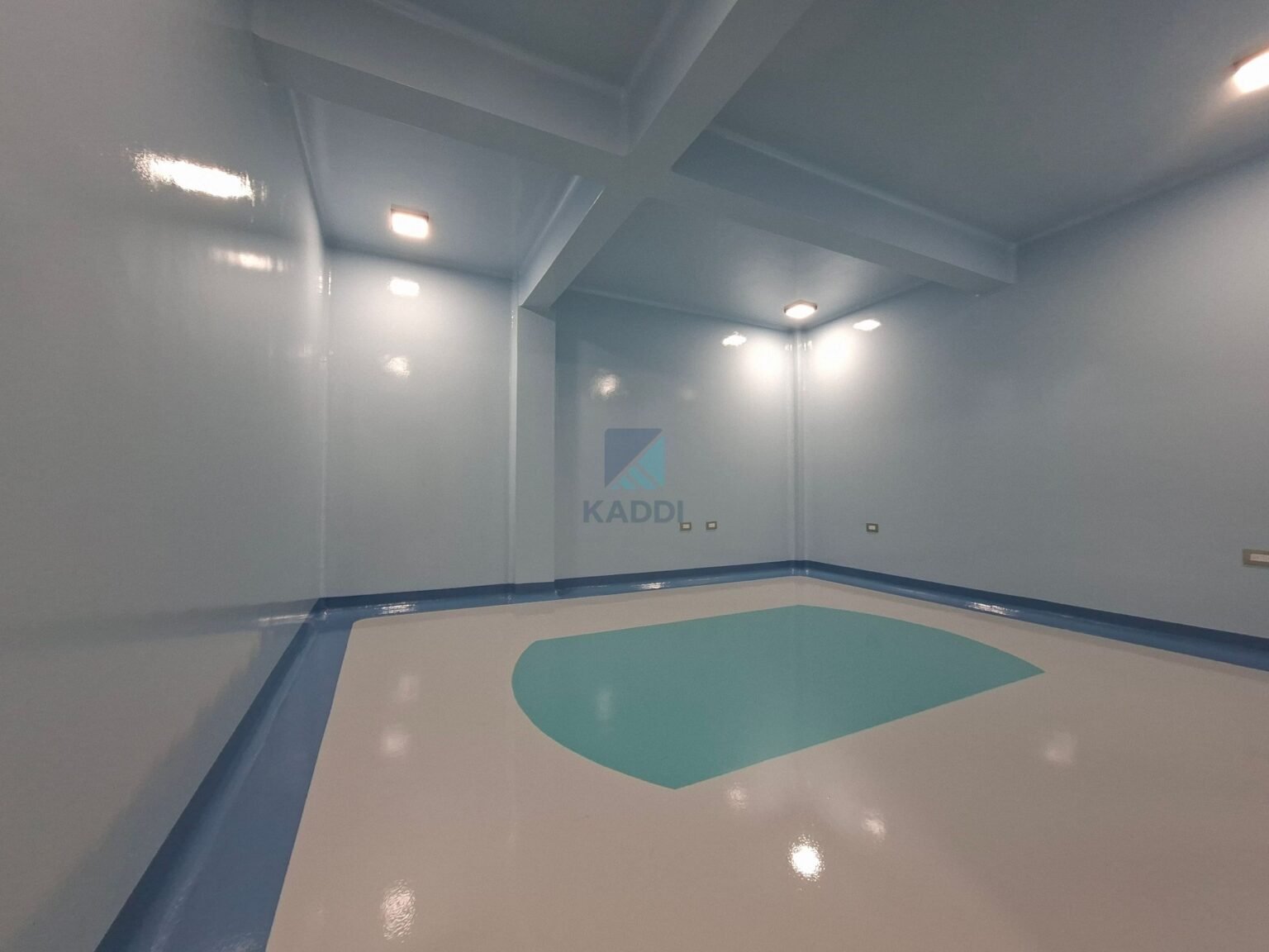 Piso epóxico blanco con detalles azules y turquesa en un área médica, aplicado por KADDI en Guatemala.