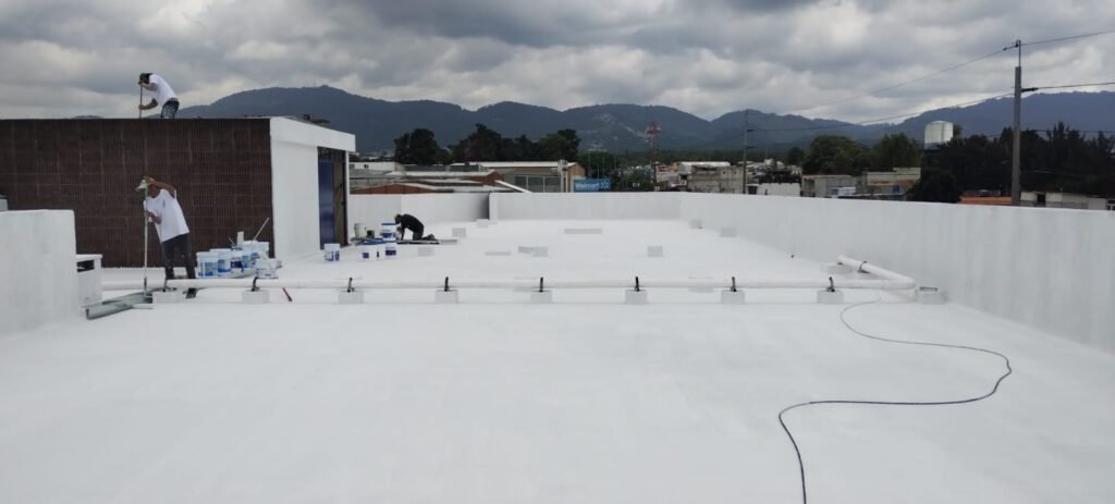 Equipo aplicando recubrimiento blanco en la cubierta de un edificio en Guatemala.